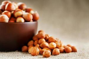 Peeled hazelnuts in a wooden, dark brown cup on a burlap cloth. Super Food, Raw. photo