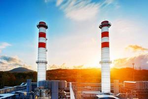 Gas Power Plant with two long pipes of white color with red poloskai on the background of mountains and sunrise in a picturesque environmentally clean place. photo