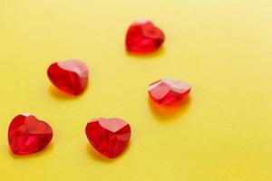 Heart shaped red crystals pattern on yellow background. Jelly crisscallic hearts on top. View from above. photo