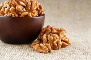 Peeled walnuts in a wooden, dark brown cup on a burlap cloth. photo