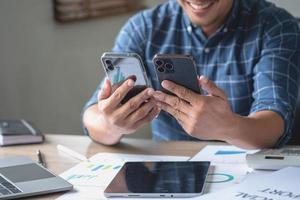 un hombre de negocios que usa dos teléfonos móviles para comunicarse con los clientes es difícil. el concepto está ocupado. foto