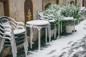 bar tables and chairs on the street with snow and ice photo