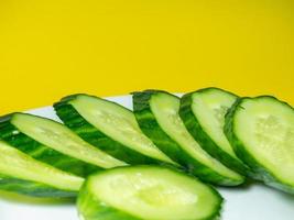 A smooth, medium-sized cucumber on white plate, sliced. Cucumber on a yellow background. photo