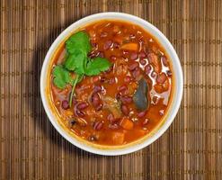 A bowl of bean soup. First course. Dinner. Tomato soup with beans, carrots, parsley and bay leaf. photo