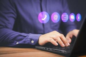 Businessman using a computer laptop with the call phone, email, address, chat message and map icons. Customer support hotline contact us people connection concept. photo