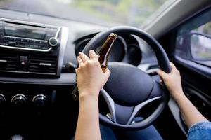 mujer bebe cerveza mientras conduce un auto. conducir en estado de embriaguez. no beber y conducir concepto foto