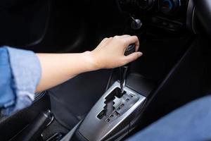 mano femenina usando un engranaje automático de coche. concepto de conducción de mujer foto