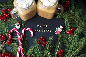 Candies and cocoa with marshmallows on a black background with the branches of trees. The inscription Merry Christmas photo