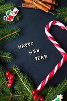 Christmas tree with ornaments and candy on a black background. The inscription Happy New Year photo