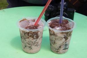 cold drink in a plastic container placed on a green table photo