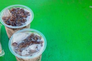 cold drink in a plastic container placed on a green table photo