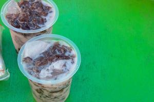 cold drink in a plastic container placed on a green table photo