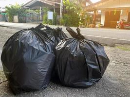 bolsas de basura negras para basura general colocadas frente a la casa asiática para esperar a que el camión de basura municipal las recoja y las deje. enfoque suave y selectivo. foto