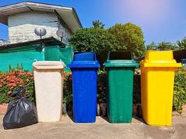 4 contenedores y bolsas de basura frente a una casa asiática donde la basura se clasifica antes de que el camión de basura la recoja, la elimine, la destruya o la recicle. enfoque suave y selectivo foto