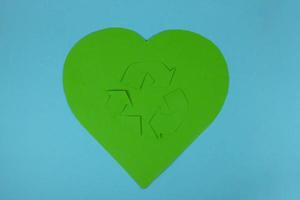 The international recycling sign Moebius loop and a heart cut out of green paper on a blue background. November 15 is the Day of recycling photo