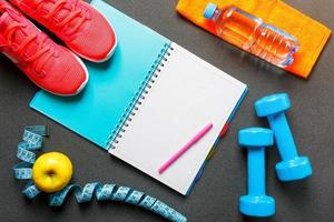 Notepad, a bottle of water, an apple, a skipping rope, dumbbells. Healthy diet, lifestyle, concept of dumbbells, exercise photo