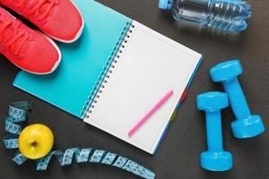 Notepad, a bottle of water, an apple, a skipping rope, dumbbells. Healthy diet, lifestyle, concept of dumbbells, exercise photo