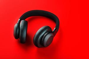 Black wireless headphones on a red background. Overhead, isolated professional-grade headphones for DJs and musicians photo