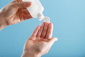 A bottle of Disinfectant gel in your hands on a blue background. Antiseptic treatment of hands from bacteria Sanitizer. photo