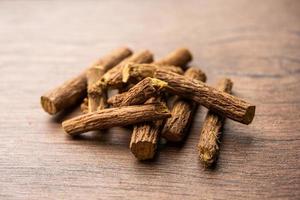 Ayurvedic Mulethi or Liquorice root stick or jeshthamadh powder served in a bowl over moody background photo