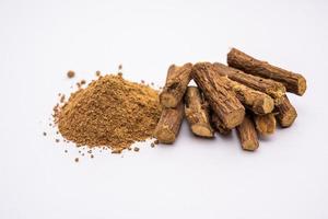 Ayurvedic Mulethi or Liquorice root stick or jeshthamadh powder served in a bowl over moody background photo