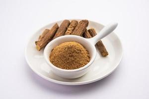 Ayurvedic Mulethi or Liquorice root stick or jeshthamadh powder served in a bowl over moody background photo