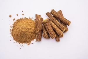 Ayurvedic Mulethi or Liquorice root stick or jeshthamadh powder served in a bowl over moody background photo