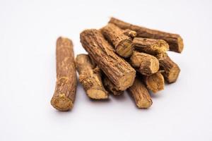 Ayurvedic Mulethi or Liquorice root stick or jeshthamadh powder served in a bowl over moody background photo