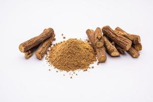 Ayurvedic Mulethi or Liquorice root stick or jeshthamadh powder served in a bowl over moody background photo