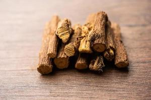 Ayurvedic Mulethi or Liquorice root stick or jeshthamadh powder served in a bowl over moody background photo