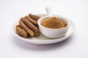 Ayurvedic Mulethi or Liquorice root stick or jeshthamadh powder served in a bowl over moody background photo