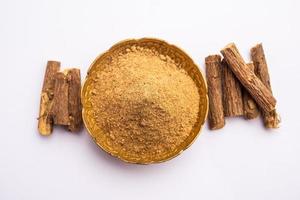 Ayurvedic Mulethi or Liquorice root stick or jeshthamadh powder served in a bowl over moody background photo