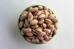 pistacho en nueces de cáscara en un recipiente sobre fondo blanco. foto