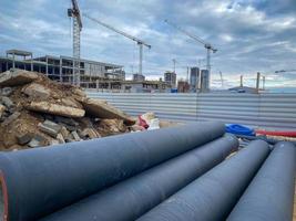 polypropylene pipes made of black material lie on a construction site. plumbing communications for new homes. construction site with crane and garbage photo