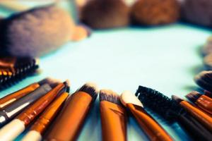 A frame from a set of beautiful different soft makeup brushes from natural lint for targeting beauty and applying a tonal foundation in a stand and copy space on a blue background photo