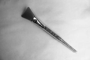 A beautiful rubber makeup brush for pointing beauty and applying a mask with a plastic gray handle and copy space on a black and white background photo