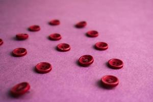 Beautiful texture with many round pink buttons for sewing, needlework. Copy space. Flat lay. Pink, purple background photo