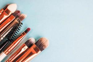 A set of beautiful different soft brushes for make-up from natural nap for beauty targeting and applying a tonal foundation in a stand and copy space on a blue background photo
