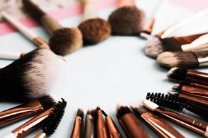 A frame from a set of beautiful different soft makeup brushes from natural lint for targeting beauty and applying a tonal foundation in a stand and copy space on a blue background photo