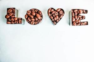 hermosa textura con la palabra amor para la inscripción del día de San Valentín hecha de granos de café arábica aromáticos naturales tostados seleccionados, espacio de copia robusta, puesta plana, fondo azul foto