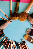 A frame from a set of beautiful different soft makeup brushes from natural lint for targeting beauty and applying a tonal foundation in a stand and copy space on a blue background photo