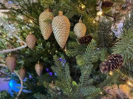 Green branches of a fluffy Christmas festive New Year tree with toys in balls and bright glowing light bulbs and garlands, background photo