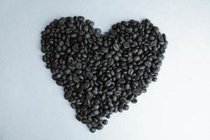 hermosa textura en forma de corazón de granos de café arábica y robusta fragantes naturales marrones saturados seleccionados recién tostados. copia espacio, endecha plana, fondo blanco aislado foto