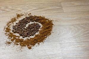 Coffee beans and ground coffee on a wooden table like a spiral. photo