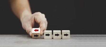 Hand flipping wooden cube block arrow from change left to right for business disruption and different thinking idea. photo