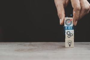 Goals Setting. Female Hand Putting Wooden Blocks With Picture Of Target, Working Gearwheels And Lightbulb Over dark  Background. Goal Achievement Concept. Motivational Collage. Panorama, Copy Space photo