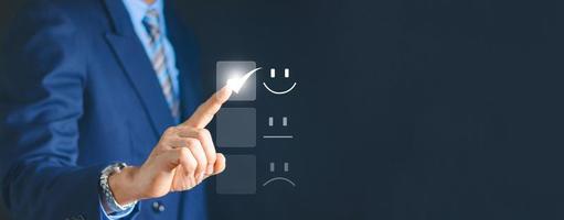 el concepto de satisfacción y servicio al cliente el hombre de negocios está tocando la pantalla virtual en el icono de la cara sonriente feliz para satisfacer el servicio. calificación muy impresionado. foto