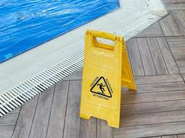 Yellow sign wet floor near the pool with water for swimming and relaxation in a hotel in a warm tropical eastern country southern resort photo