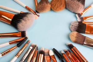 A frame from a set of beautiful different soft makeup brushes from natural lint for targeting beauty and applying a tonal foundation in a stand and copy space on a blue background photo