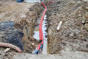 Large red plastic corrugated pipes with wires for a transformer substation at a construction site during a repair in a new underground community photo